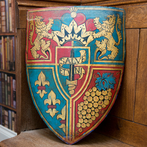 A sample hand-Painted Bespoke Coat of Arms Shield dispalying a particular heraldry, placed on a wooden chair in a library.
